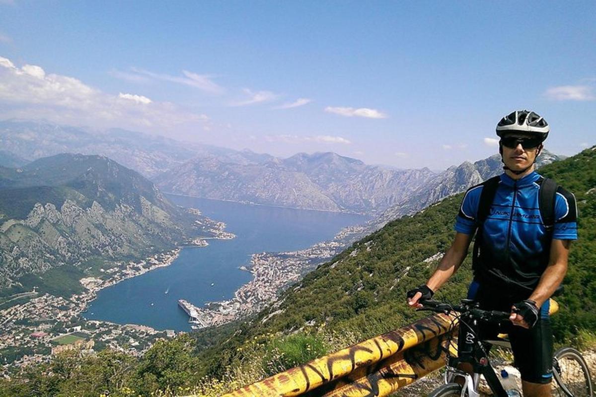 moški, ki stoji na kolesu na vrhu gore