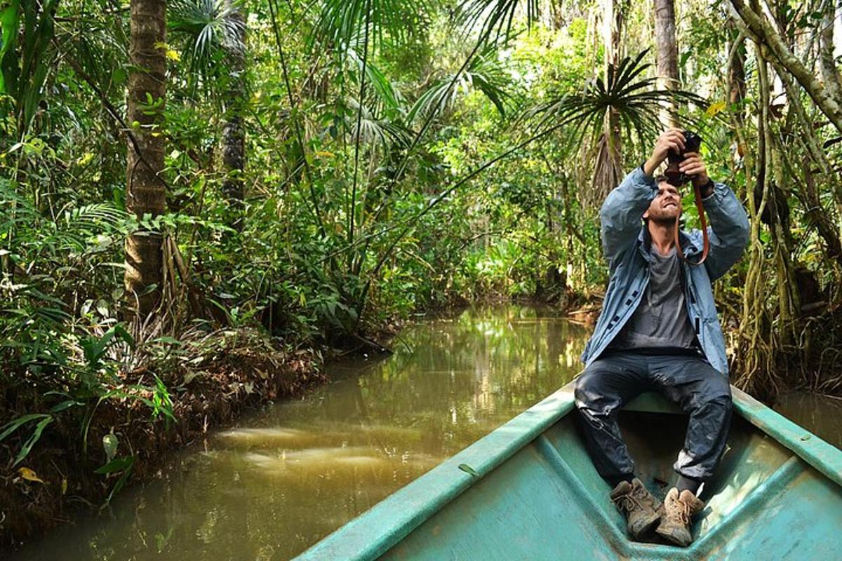 a man sitting in a boat in the jungle