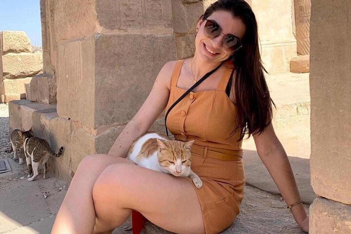 una donna con un vestito arancione che tiene in braccio un gatto