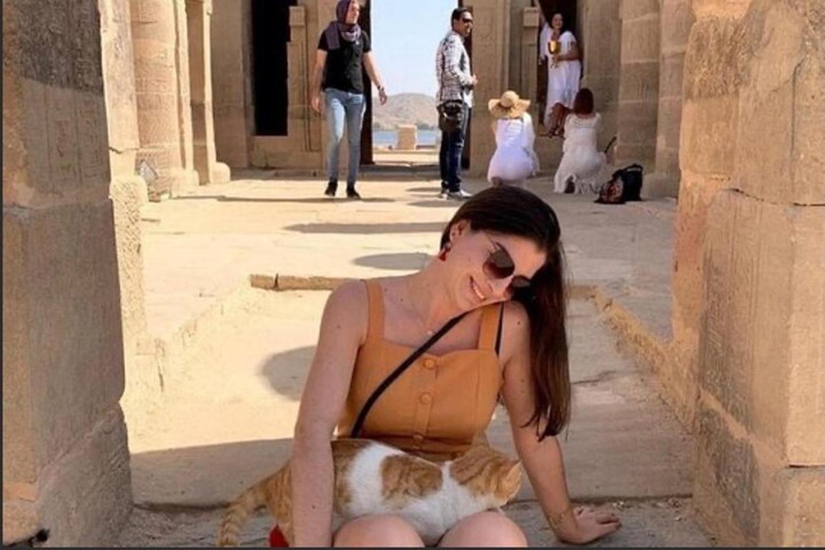 una donna seduta a terra con un gatto