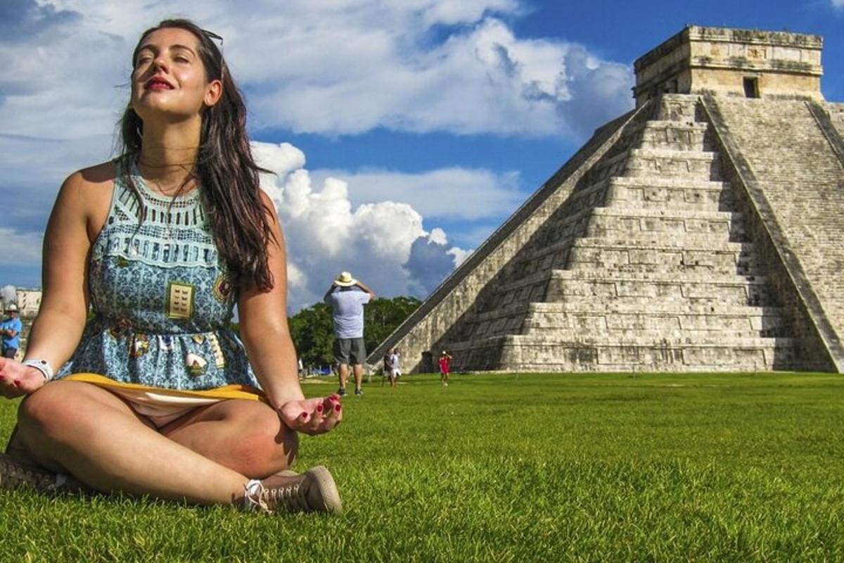 isang babaeng nakaupo sa damuhan sa harap ng isang pyramid