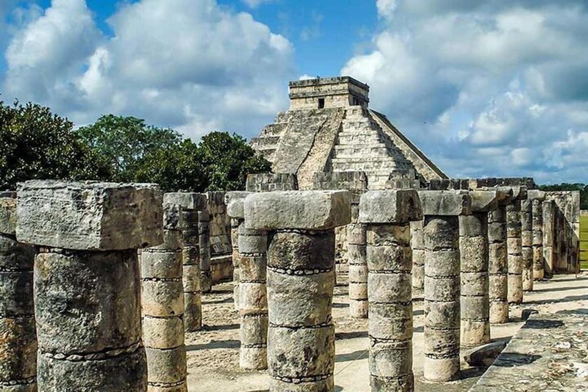 uma fileira de colunas em frente a uma pirâmide