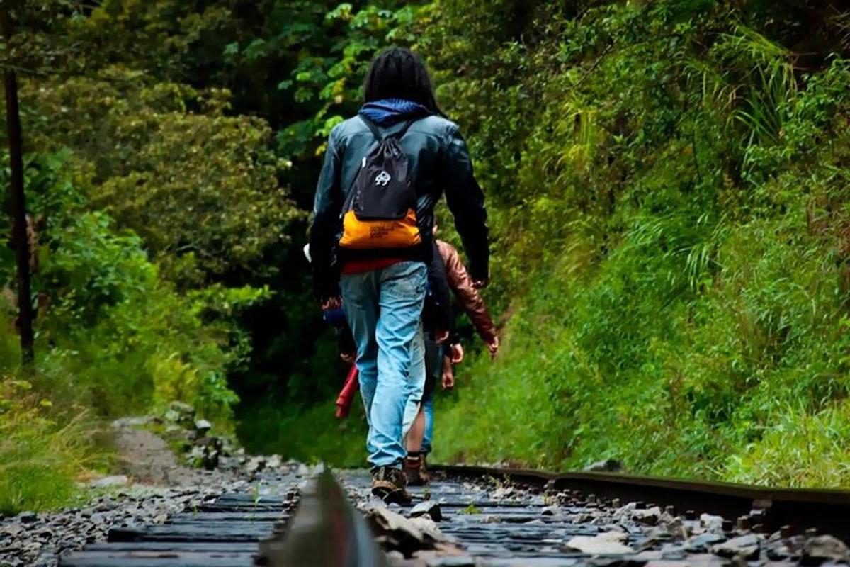 isang lalaking may backpack na naglalakad sa riles ng tren