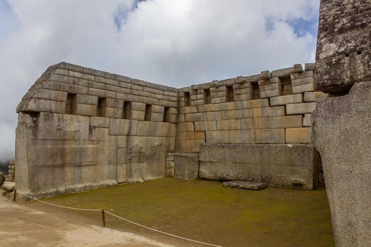 un grande muro di pietra con un campo verde all'interno