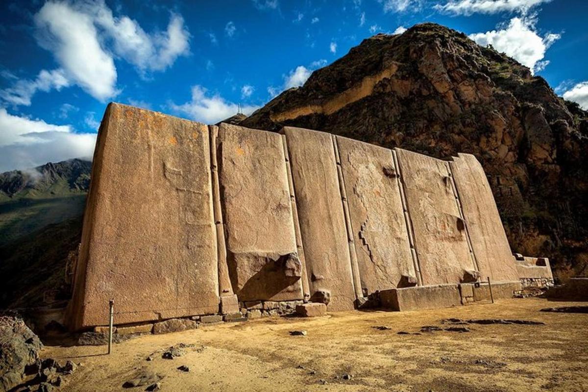a large stone wall in front of a mountain