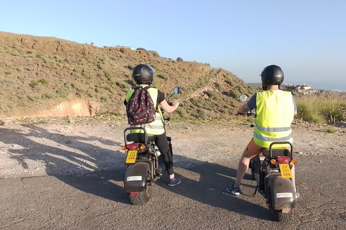 toprak yolda motosiklet süren iki kişi