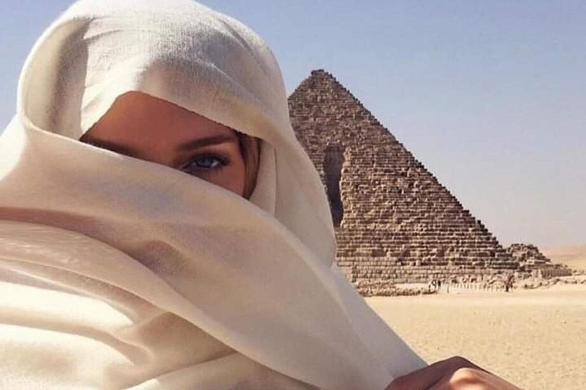 žena v hidžábu stojící před pyramidami