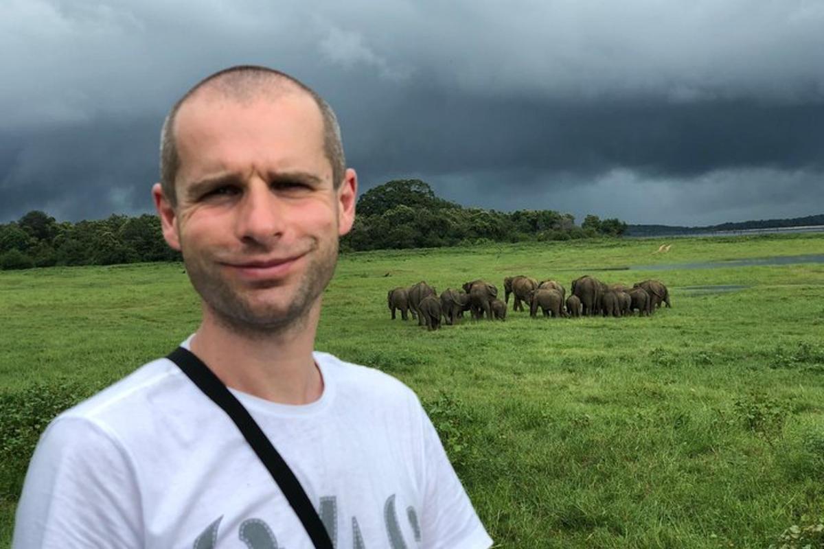 seorang lelaki berdiri di padang dengan sekumpulan gajah