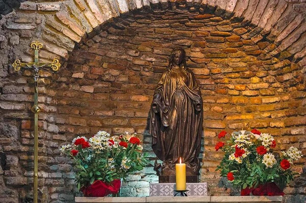 Una estatua en una iglesia con flores y una vela.