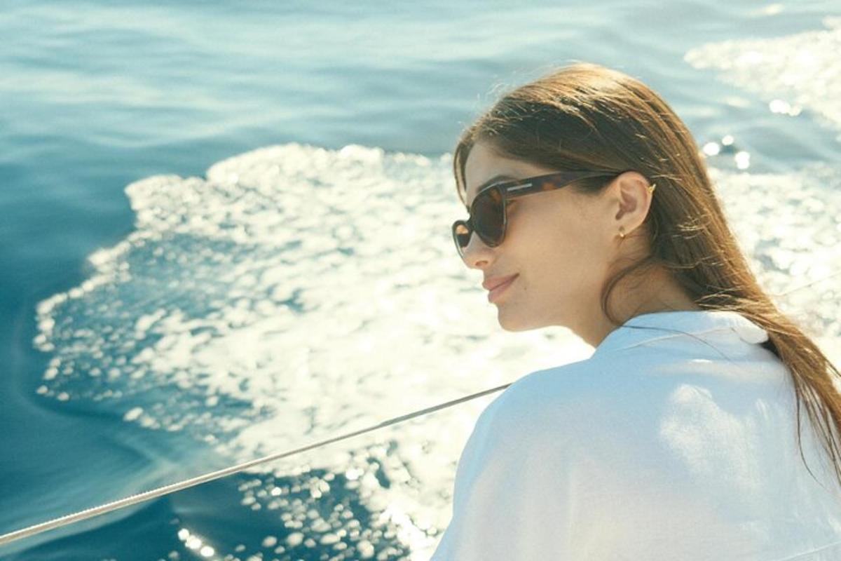 a woman wearing sunglasses standing on a boat in the water