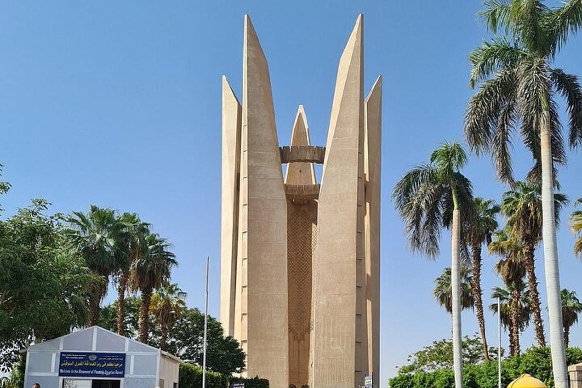 sebuah gedung tinggi dengan menara jam di samping pohon palem