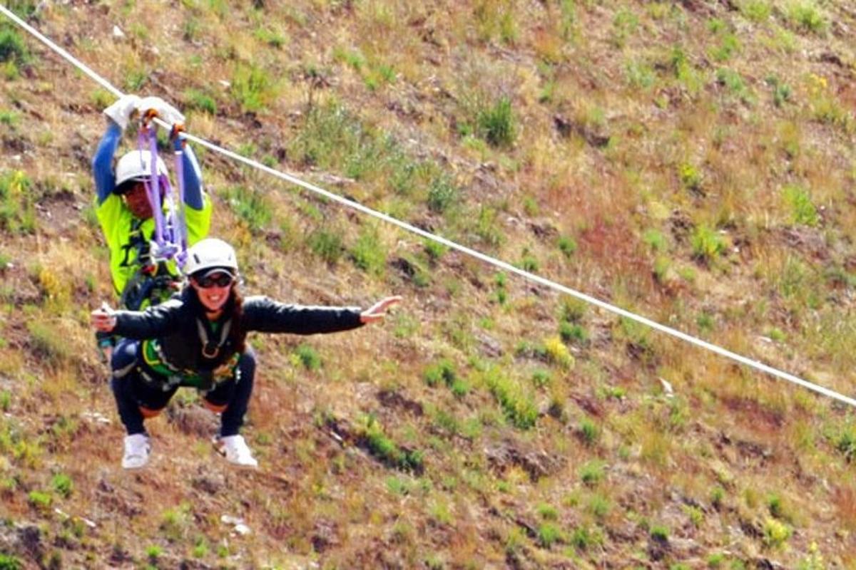 two people on a zip line on a hill