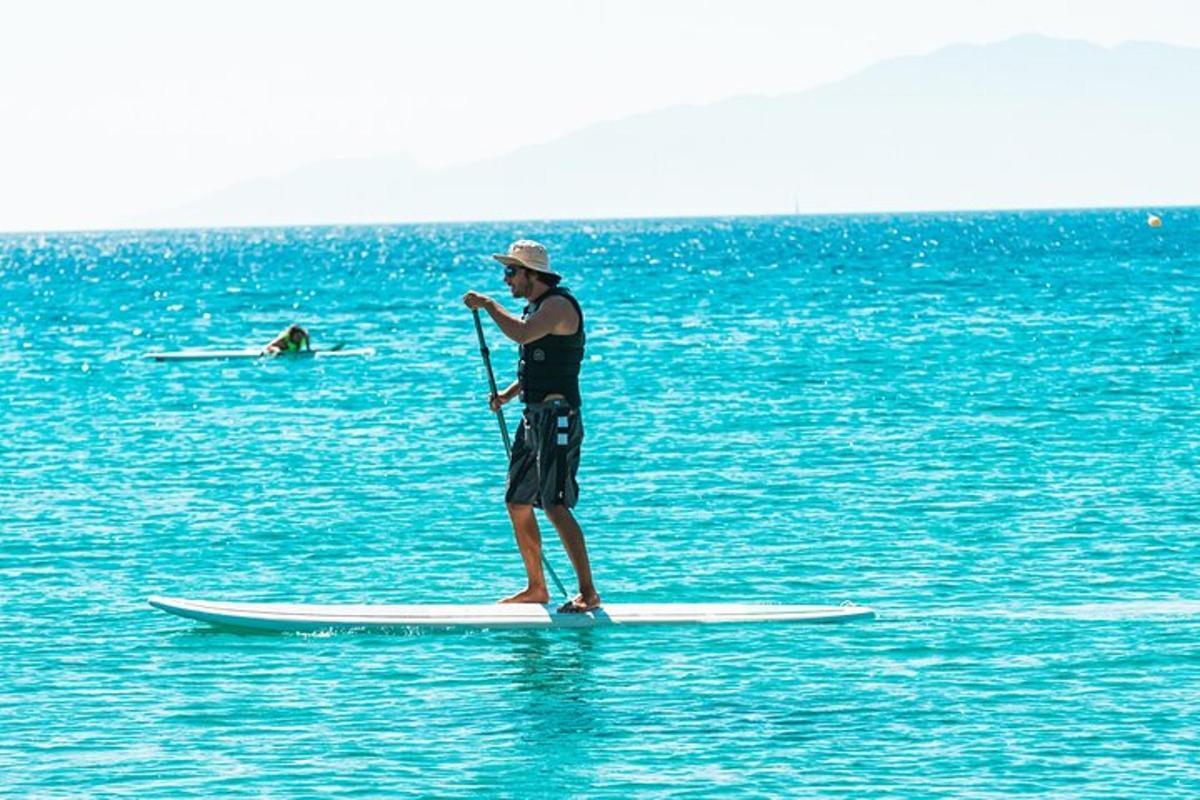muž stojící na paddleboardu v oceánu
