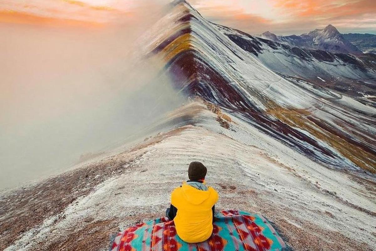 un uomo seduto su un elefante che guarda una montagna