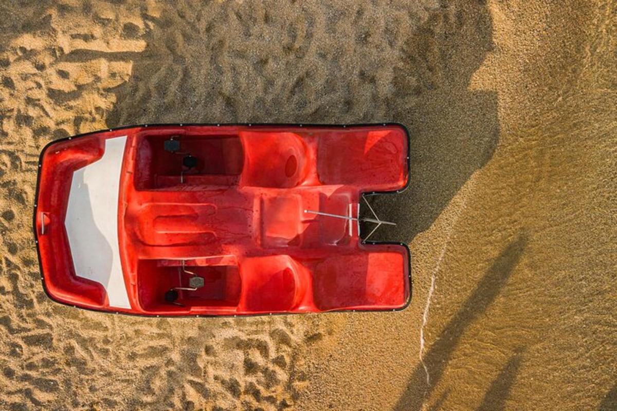 un'auto rossa parcheggiata nella sabbia della spiaggia