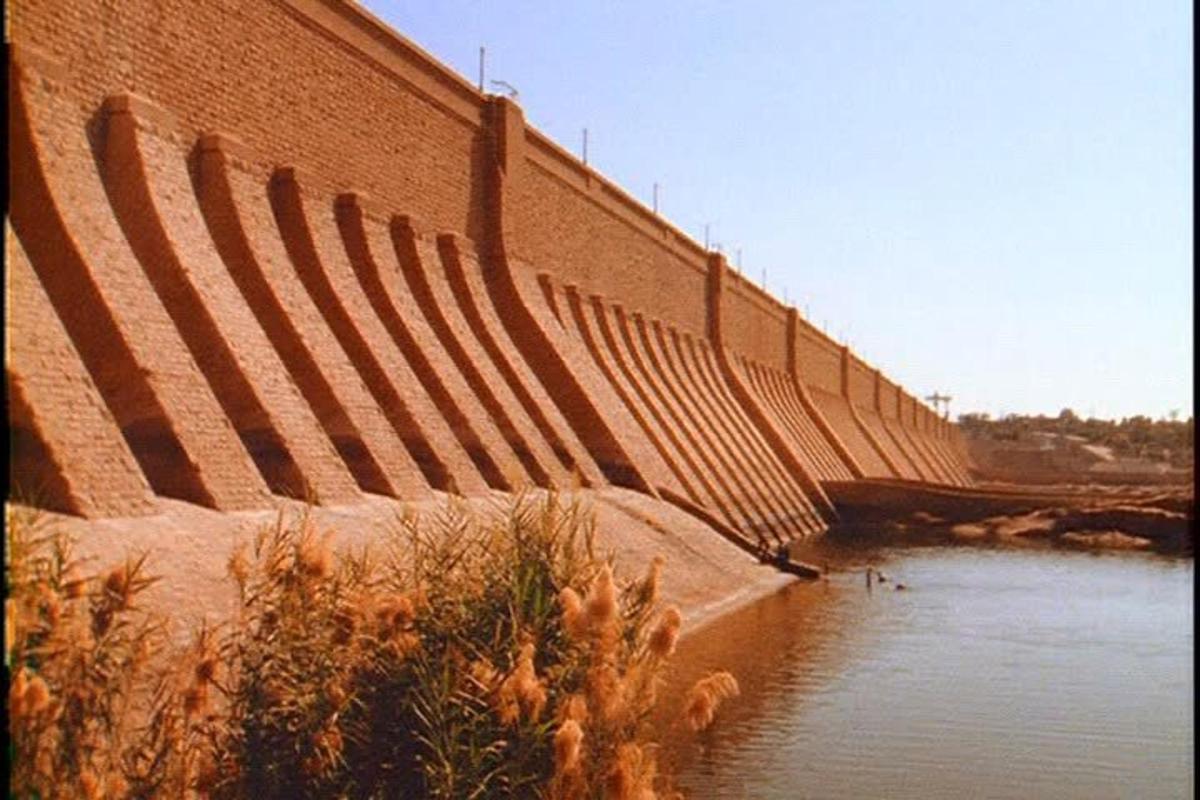 een grote bakstenen muur naast een waterlichaam