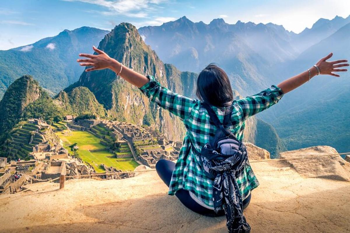 seorang wanita duduk di puncak gunung dengan tangan terentang