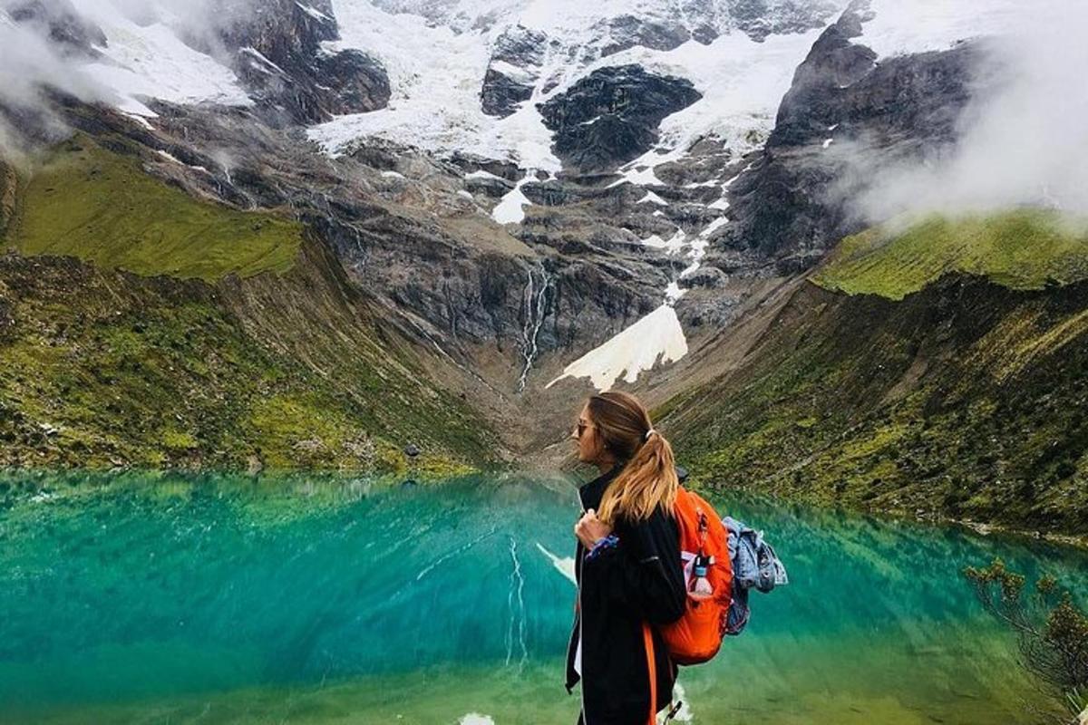uma mulher com uma mochila em pé em frente a um lago
