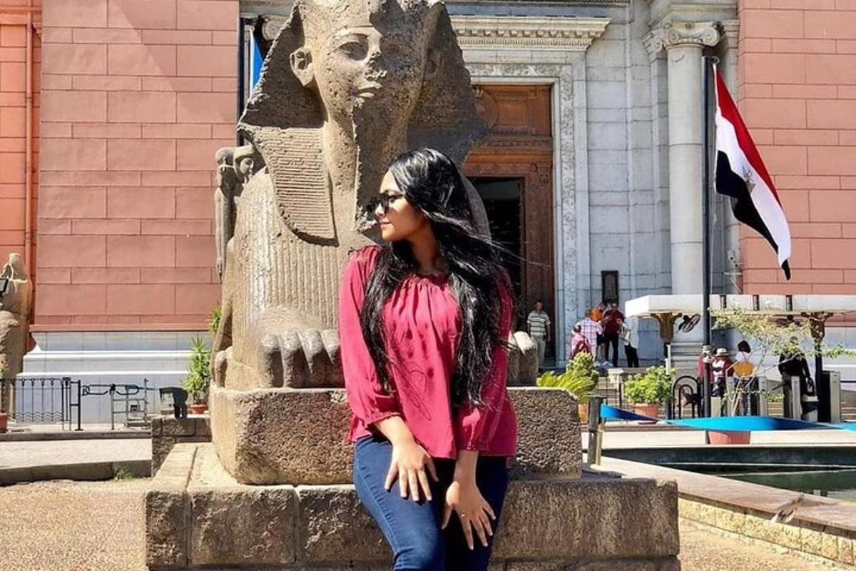 Una mujer sentada junto a una estatua frente a un edificio.