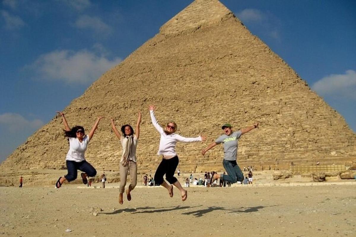 Skupina lidí skáče před pyramidami
