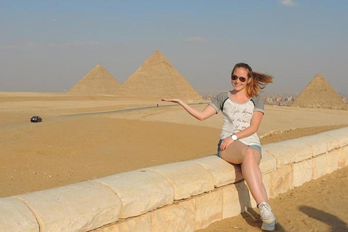 žena sedící na zdi před pyramidami