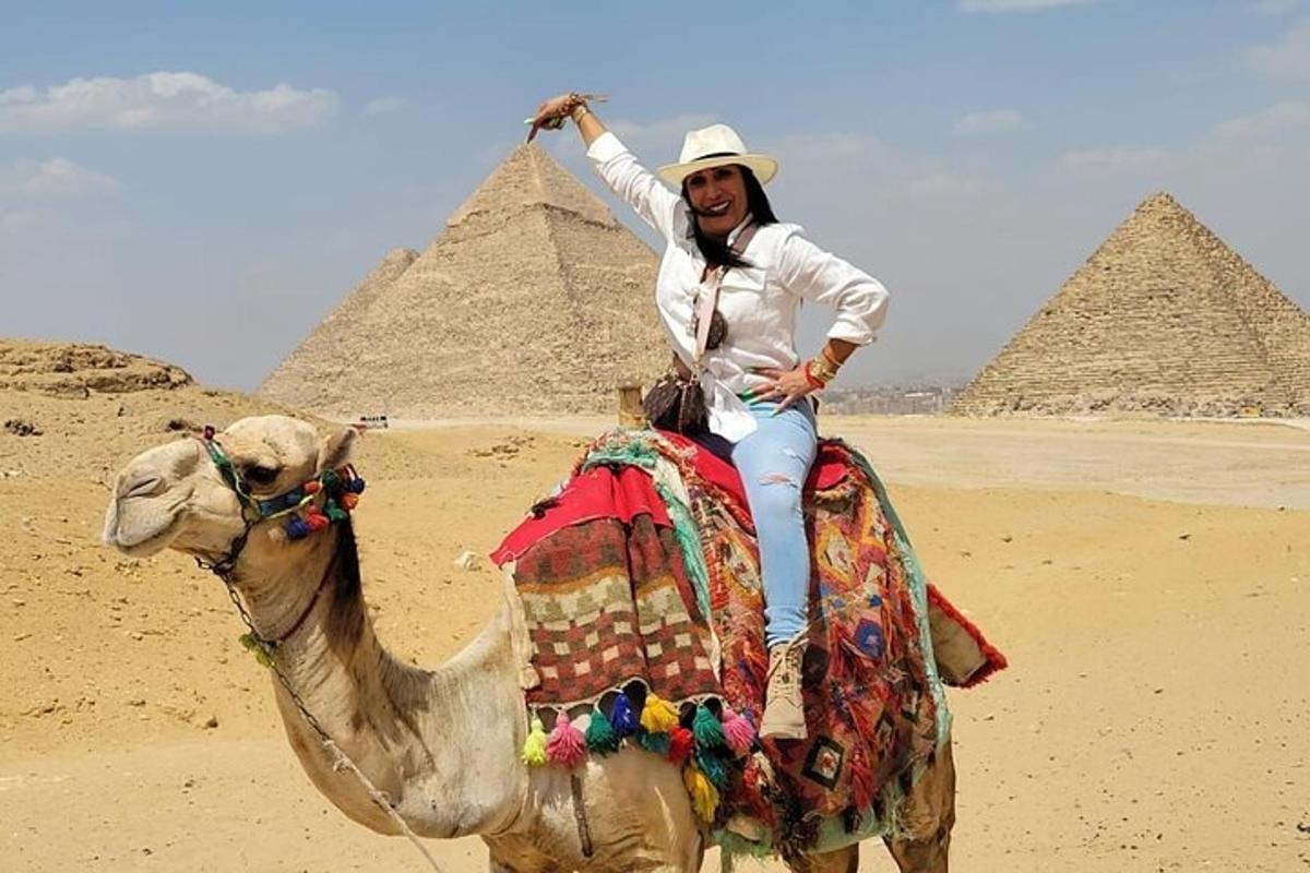 žena jedoucí na velbloudovi před pyramidami