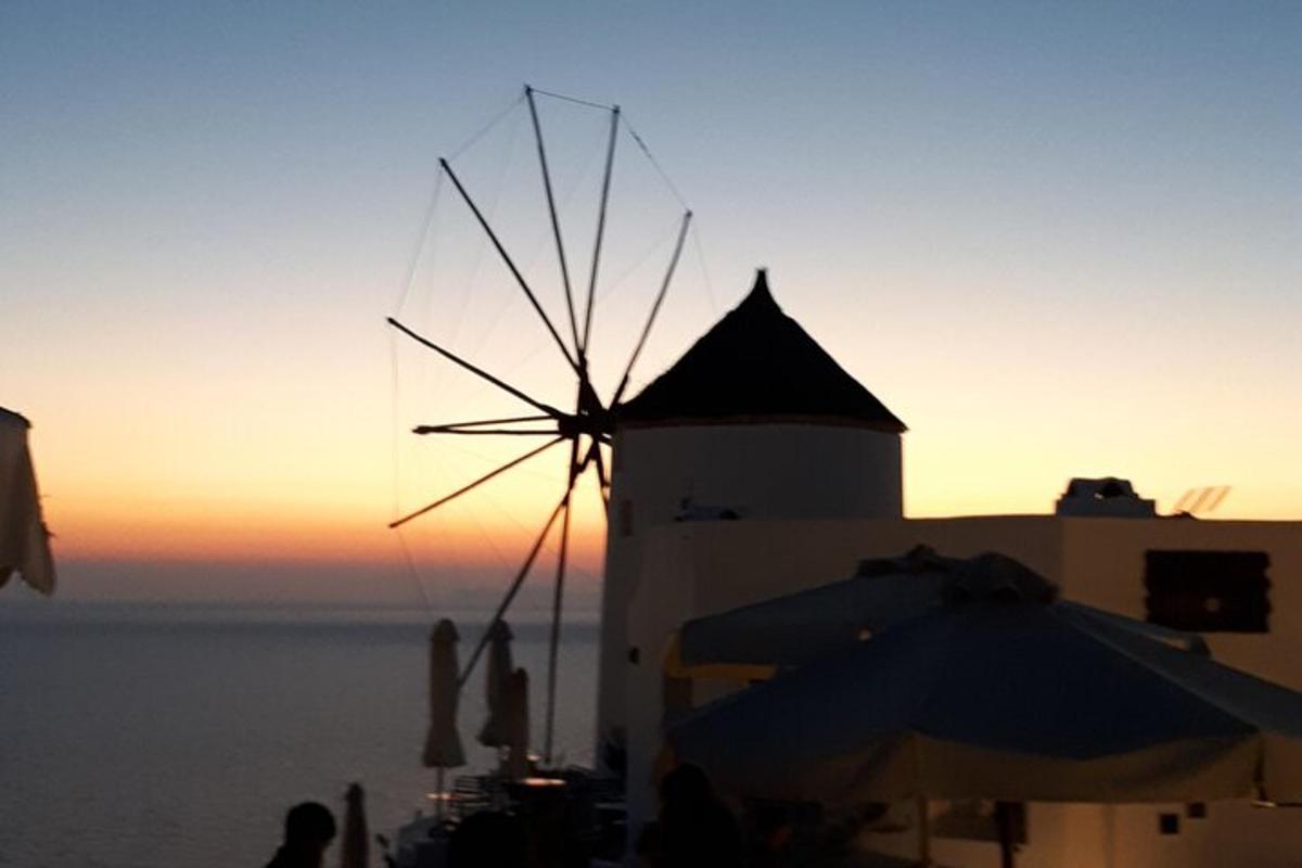 Un molino de viento en la playa con la puesta de sol de fondo