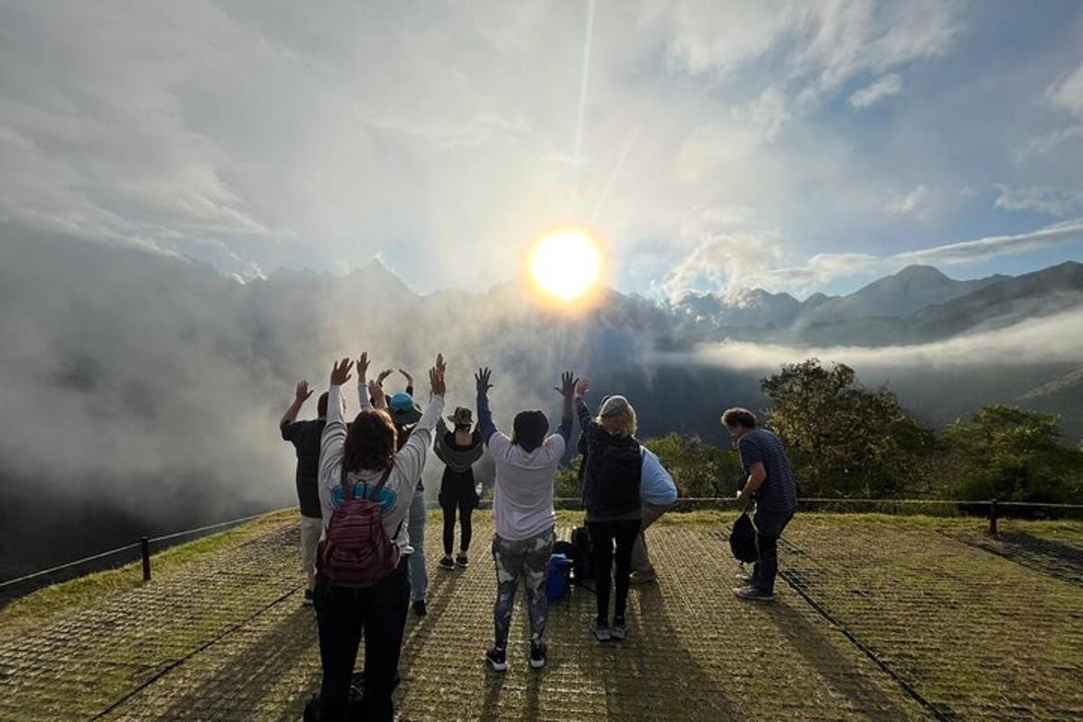 um grupo de pessoas em pé no topo de uma montanha com as mãos para cima