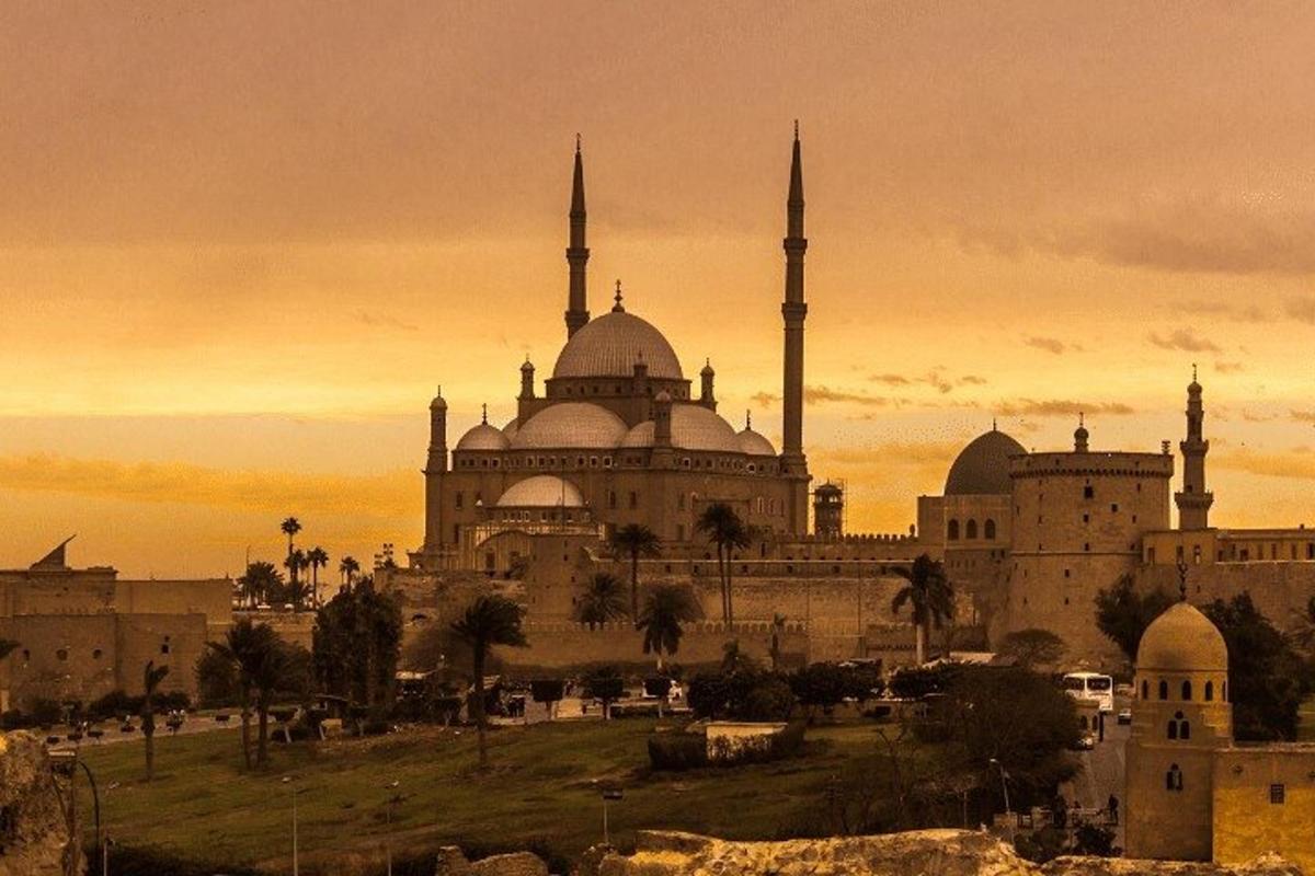 um edifício com duas mesquitas com um pôr do sol ao fundo