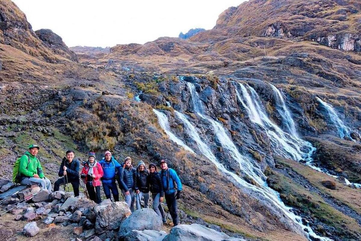 sekumpulan orang berdiri di hadapan air terjun