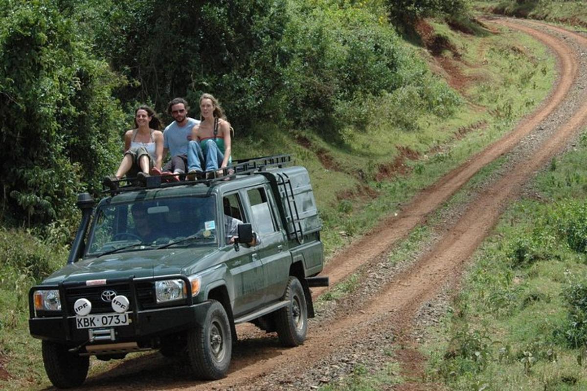 three people sitting on top of a green truck on a dirt road