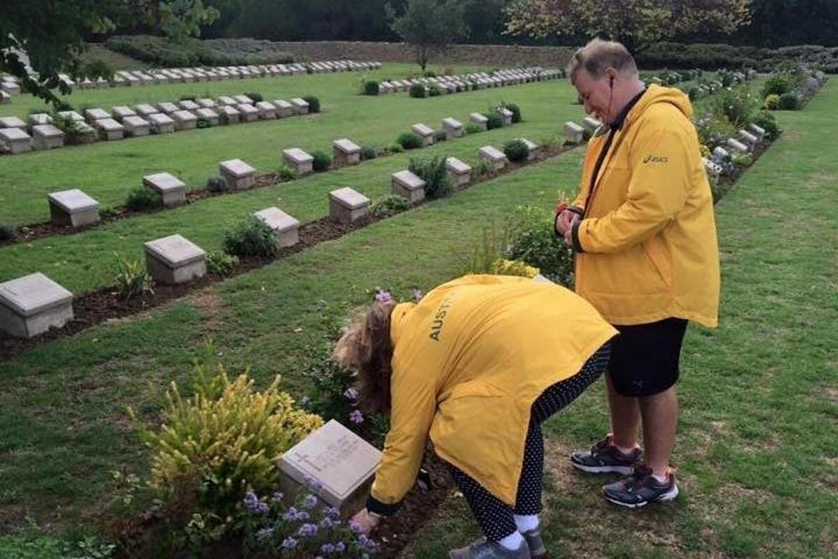 dues persones dretes en un cementiri mirant flors