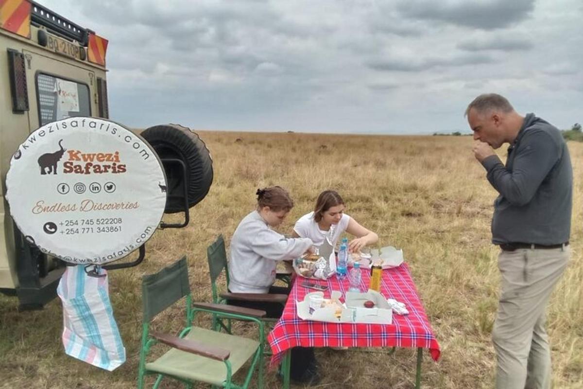 skupina lidí sedících u piknikového stolu na poli