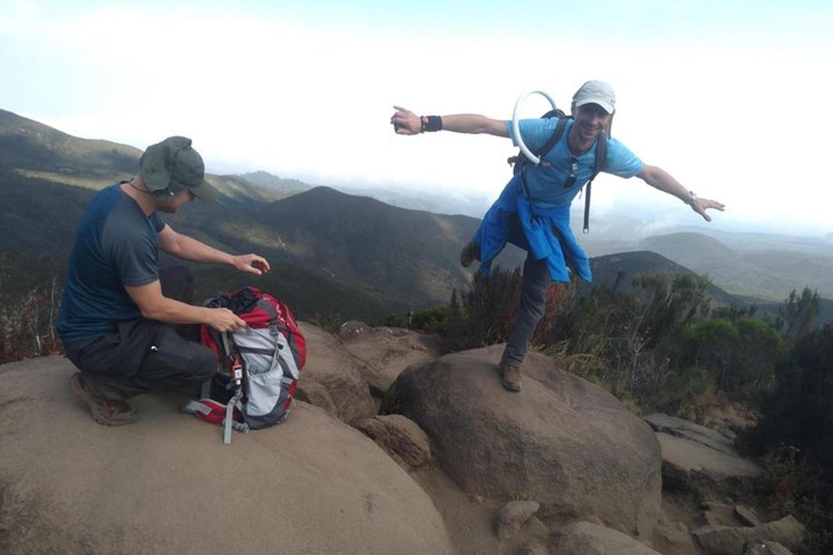 two people standing on a rock on a mountain