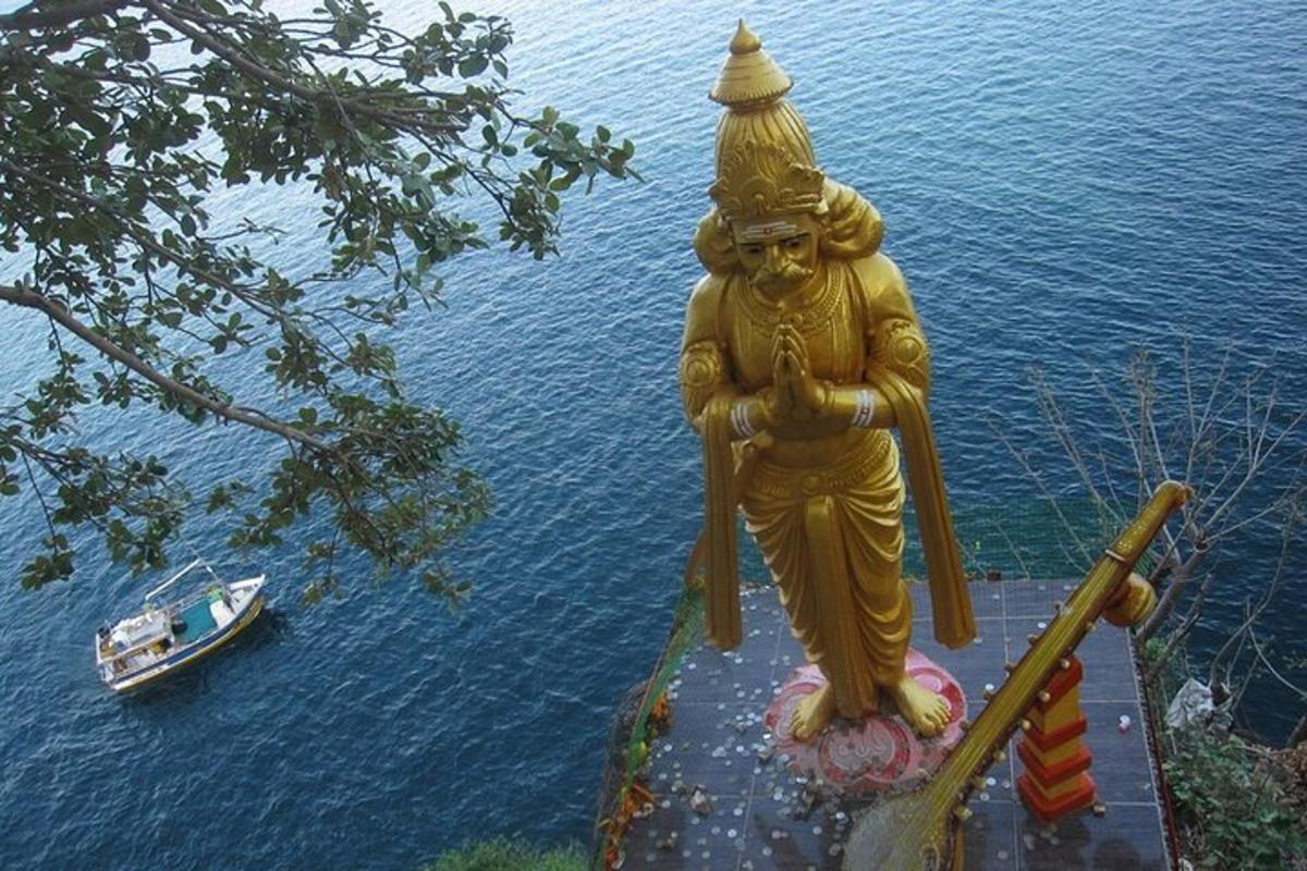 Una gran estatua amarilla junto al agua con un barco.