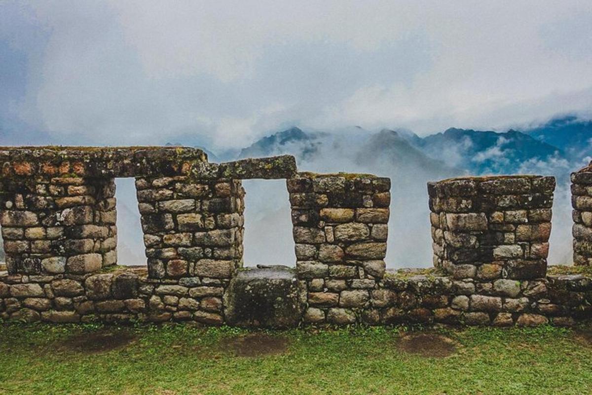 um muro de pedra com duas janelas em um campo