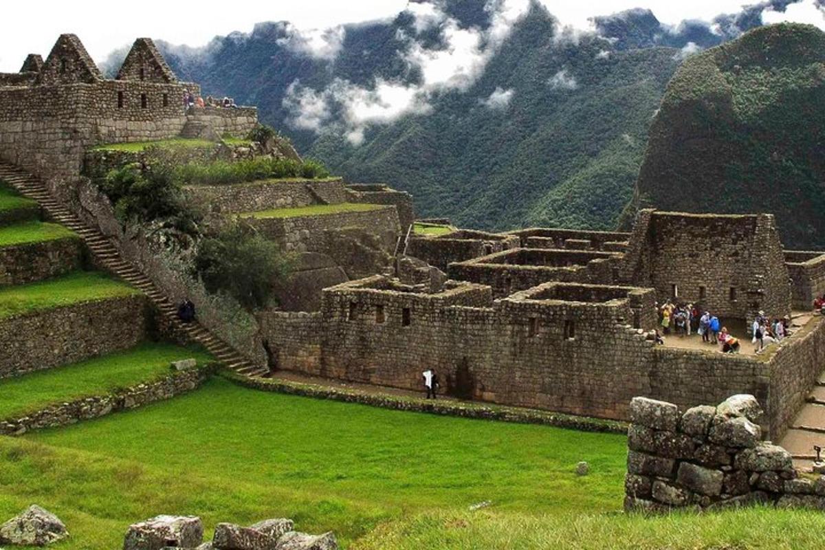people walking around an old building with mountains in the background