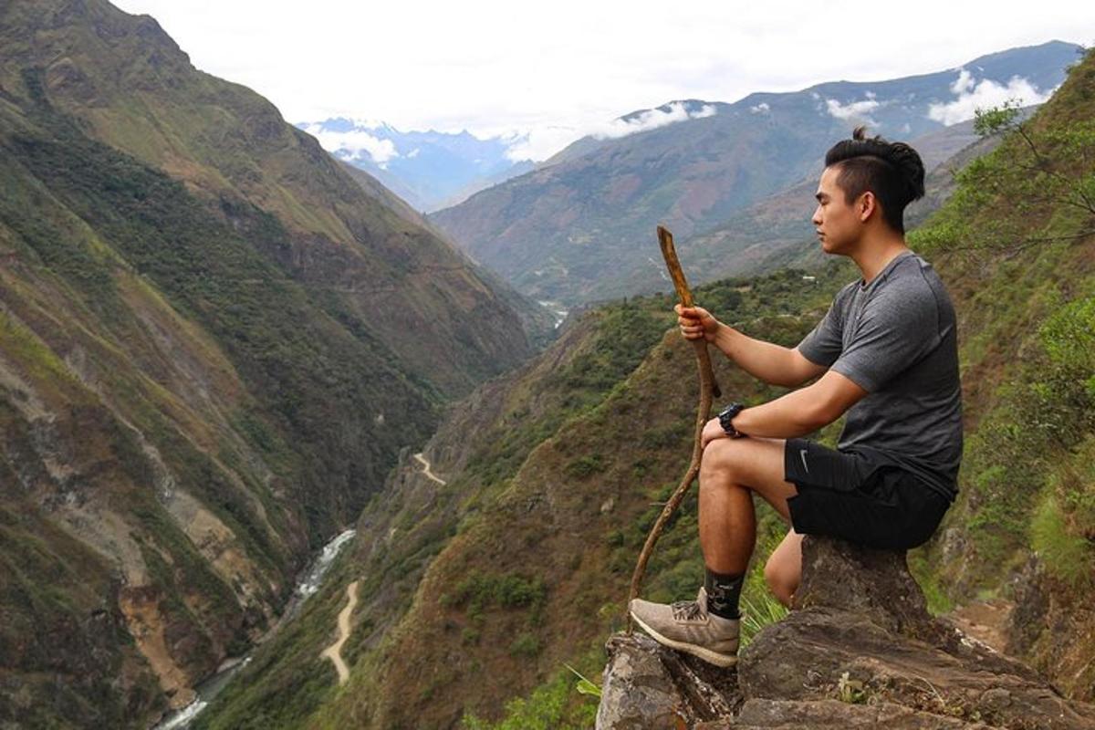 a man sitting on a rock with a stick