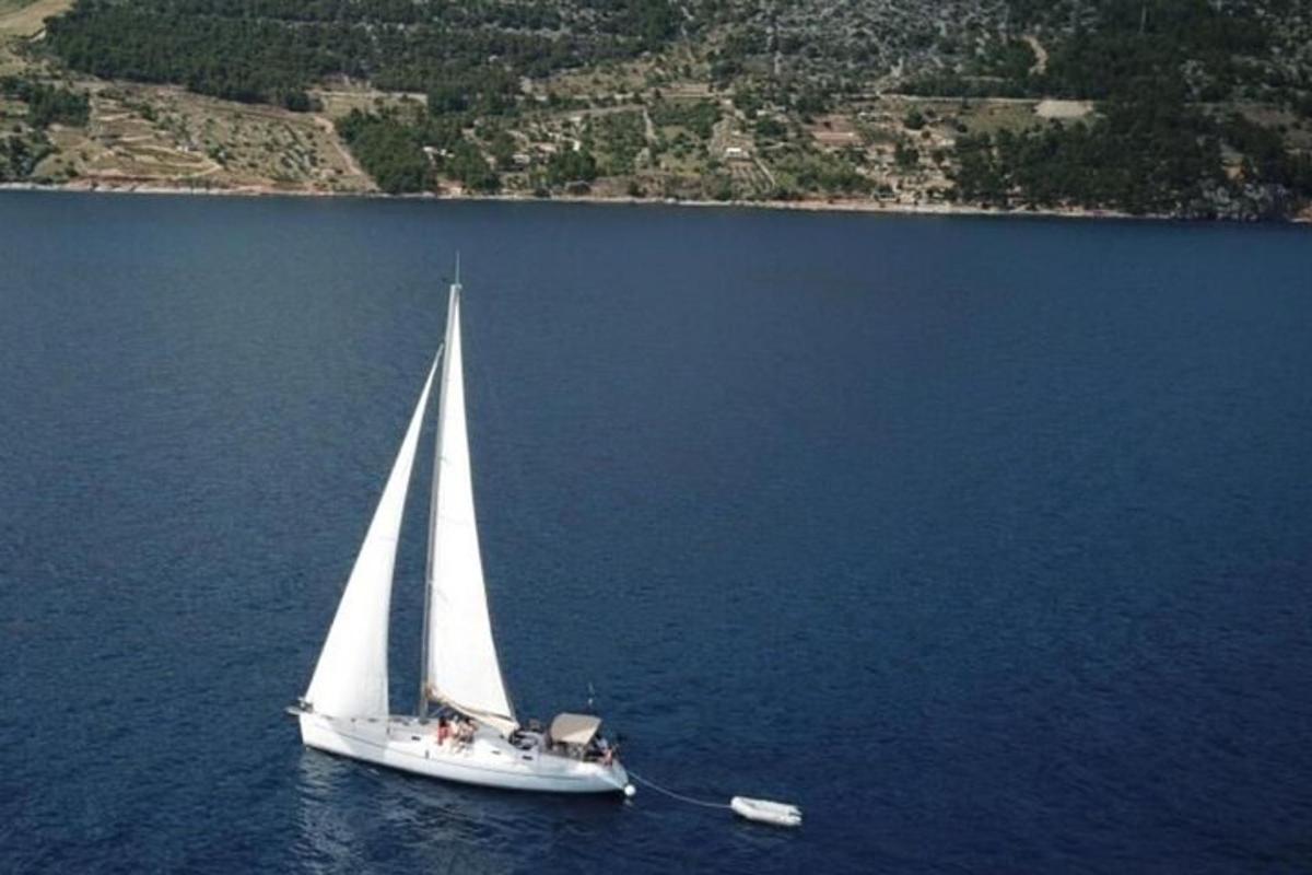 perahu layar putih di air dengan sebuah pulau