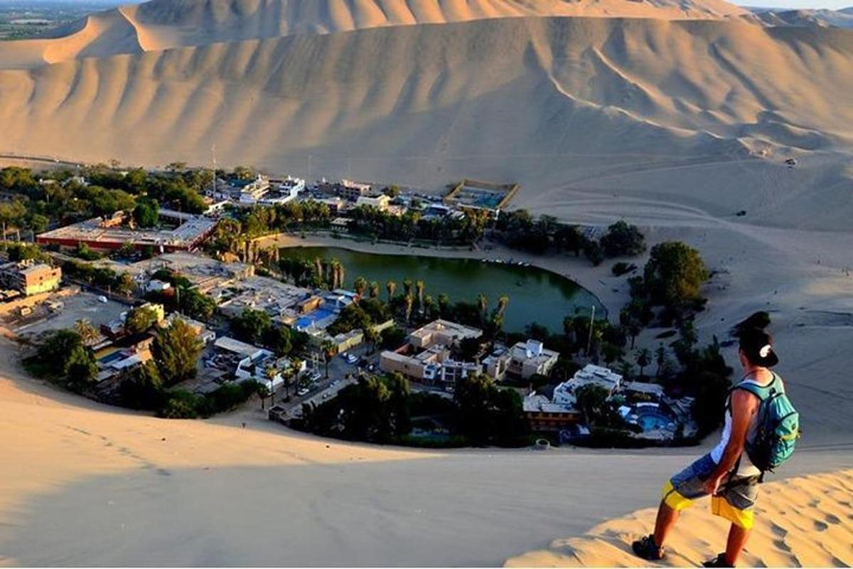 a man walking on top of a sand dune