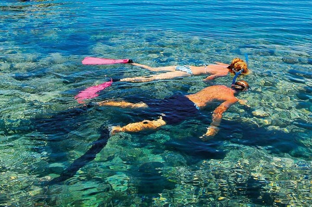 tiga orang berenang di air