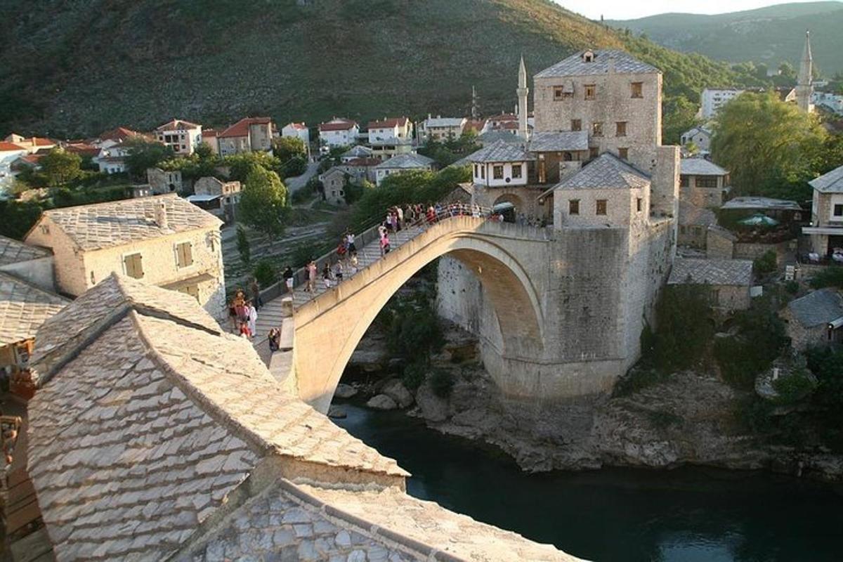 μια ομάδα ανθρώπων που διασχίζει μια γέφυρα πάνω από ένα ποτάμι