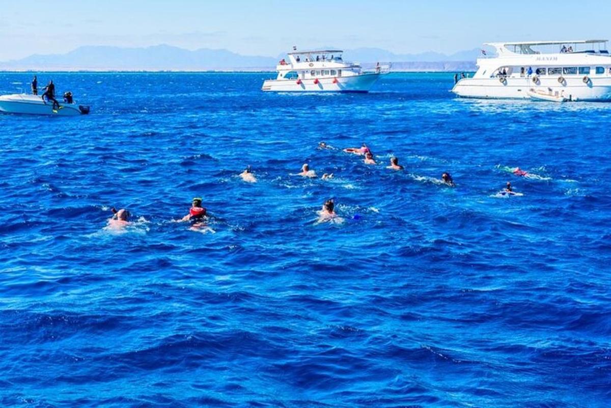 skupina lidí plave v oceánu s loděmi