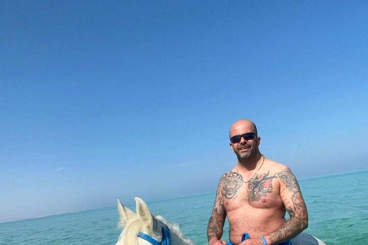 muž jedoucí na bílém koni v oceánu