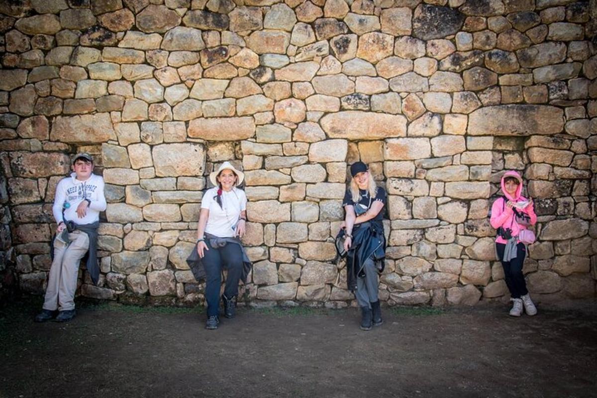 um grupo de mulheres sentadas contra um muro de pedra
