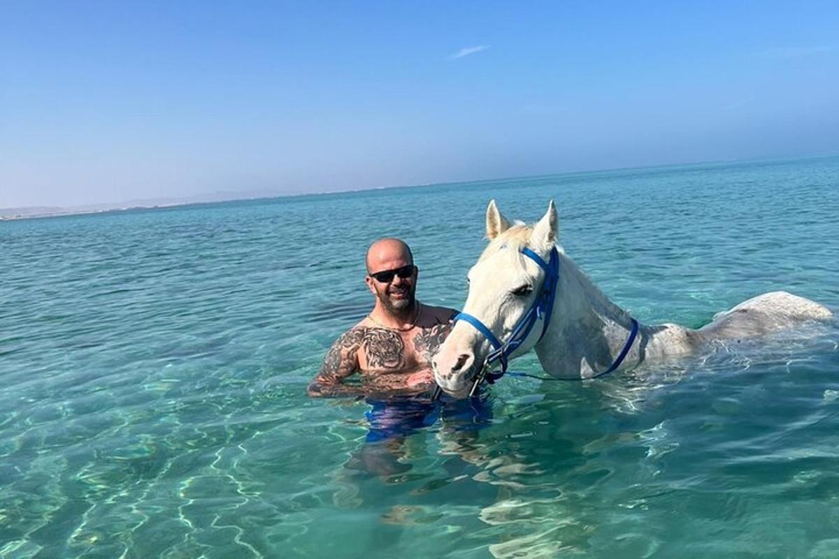 moški v vodi s konjem v oceanu
