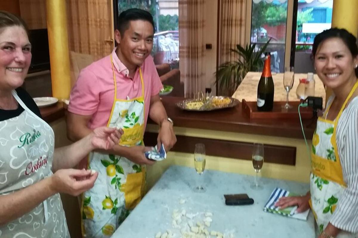 seorang pria dan dua wanita berdiri di sekitar meja dengan gelas anggur