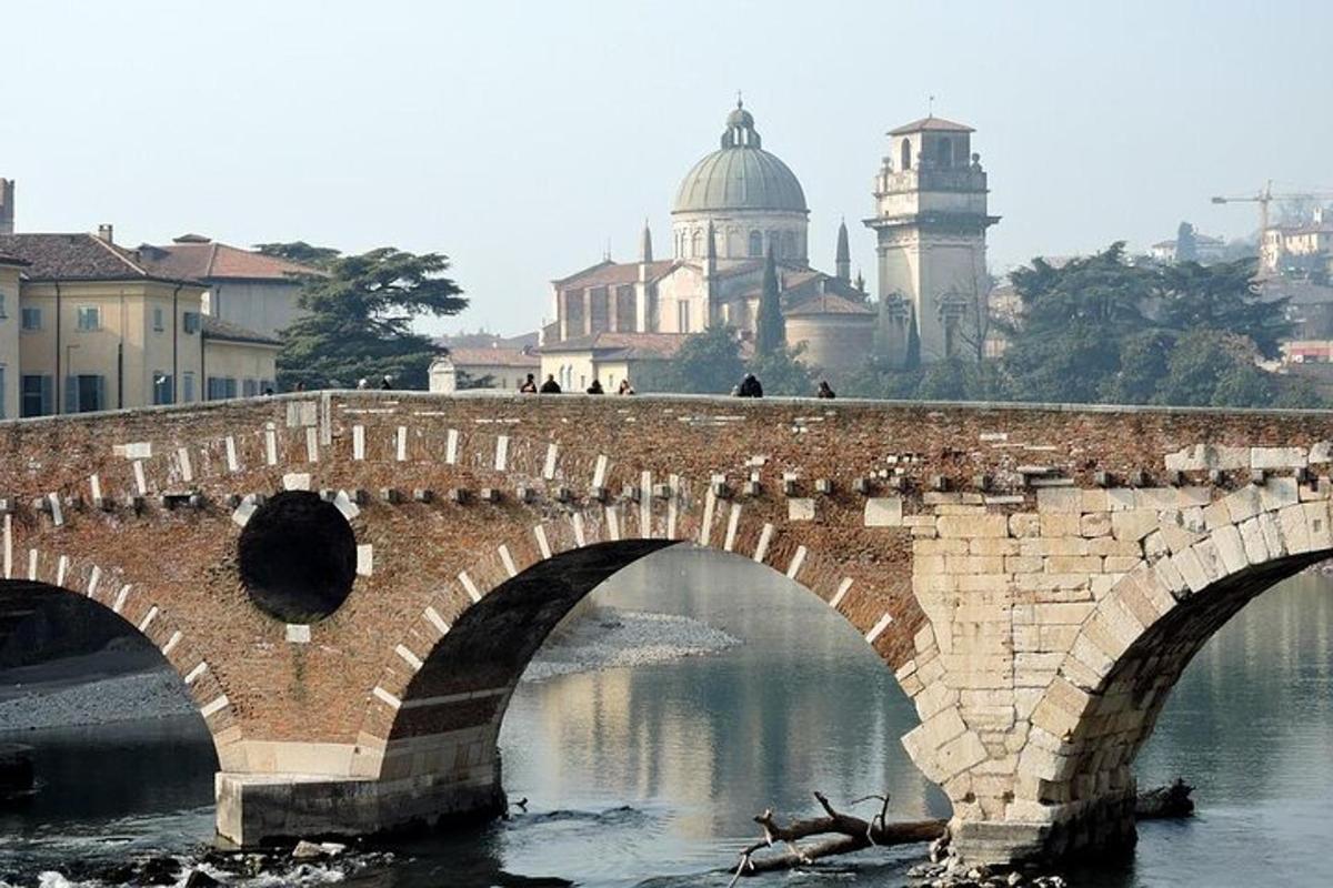 Un puente de ladrillo sobre un río con edificios al fondo.