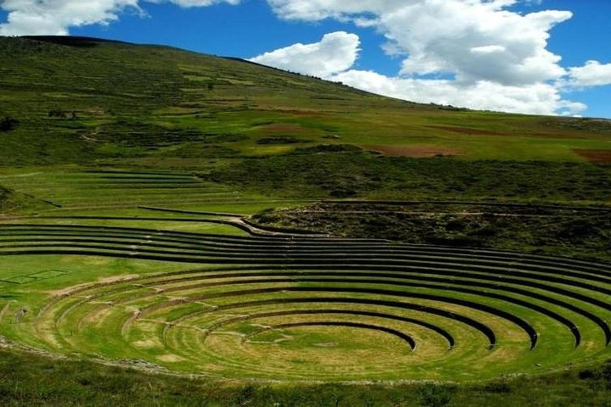 an amphitheater in a green field with a hill