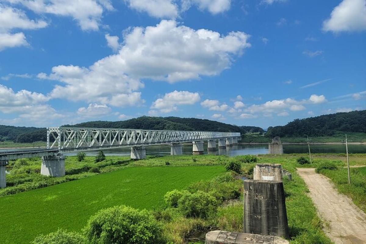 Un puente sobre un río con un campo verde.